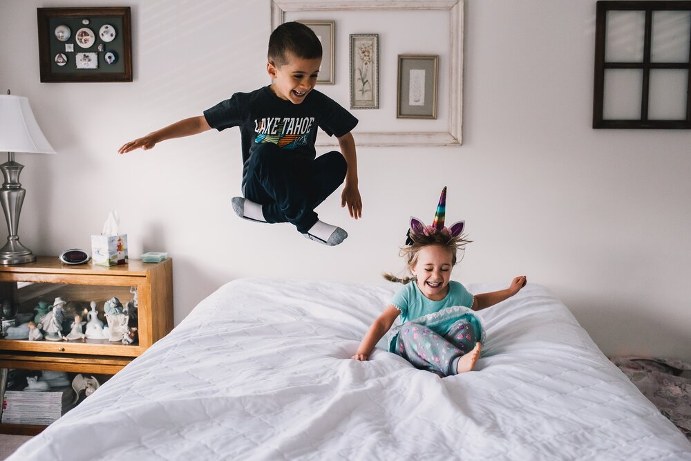 siblings jumping on the bed
