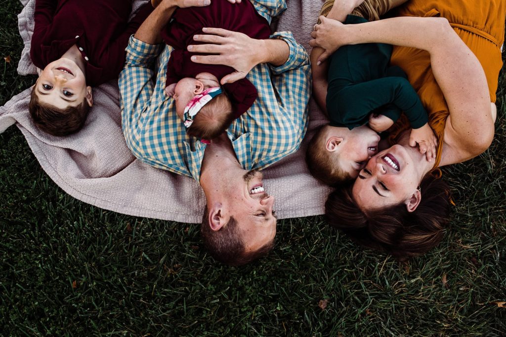 family of 5 laying in grass and laughing for fall family photos