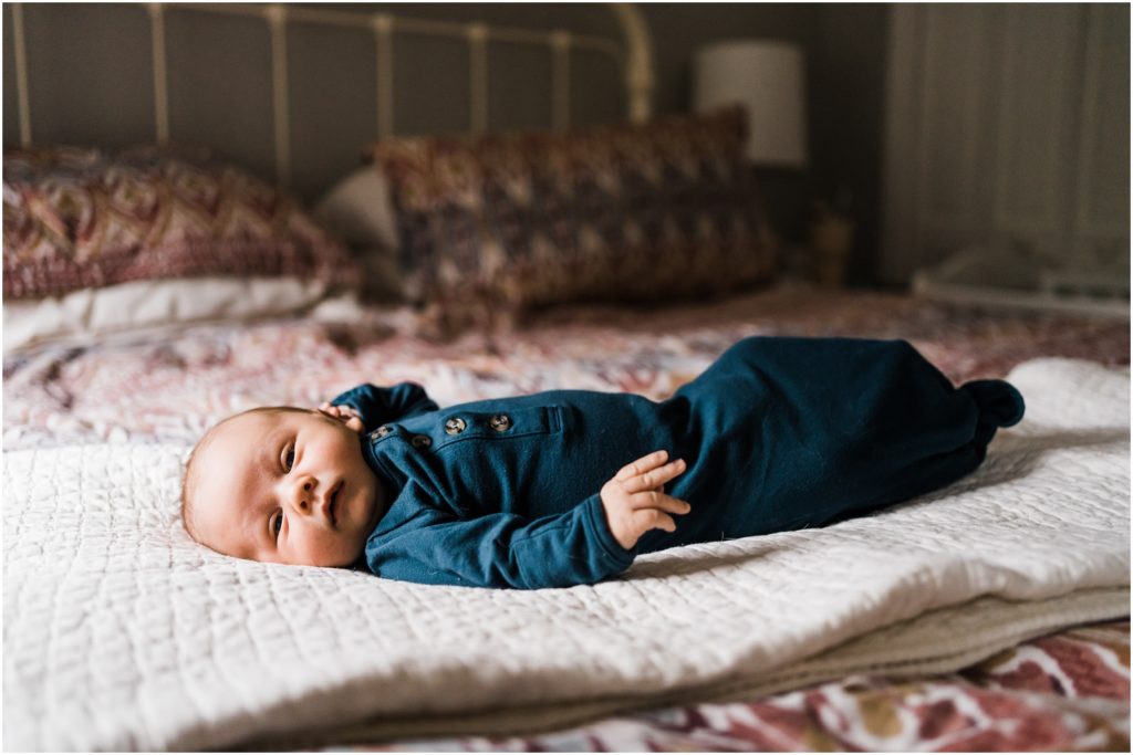baby laying on bed in solid onsie