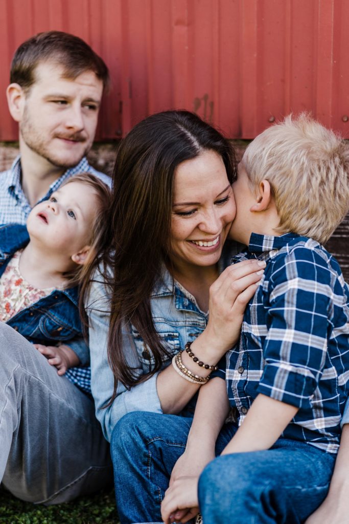 pose ideas for family of four against a barn with charlottesville family photographer