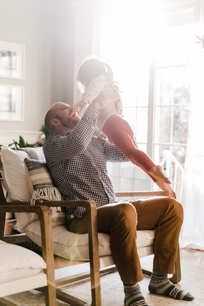 playful moment between father and daughter in lifestyle family photos at home