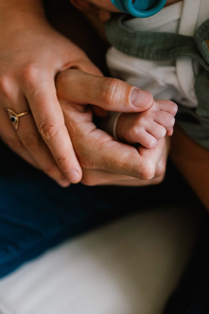 photo of mom and dad with newborn baby hand, detail shot for in-home newborn photos 